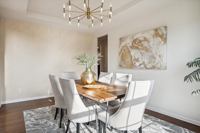 dining space featuring a chandelier, dark wood-type flooring, and a tray ceiling