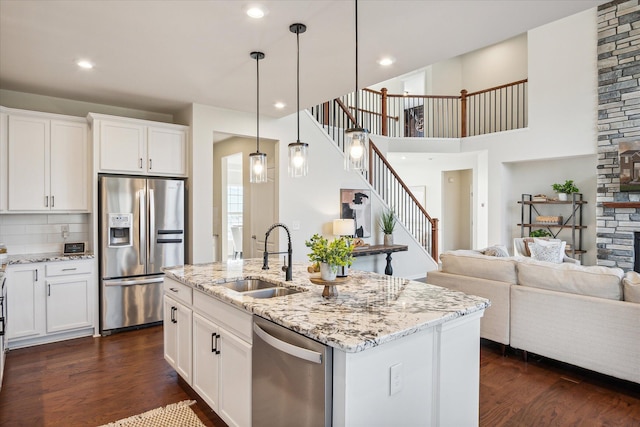 kitchen with white cabinetry, sink, appliances with stainless steel finishes, and an island with sink