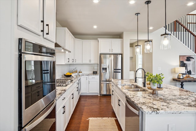 kitchen with backsplash, a kitchen island with sink, sink, white cabinetry, and stainless steel appliances