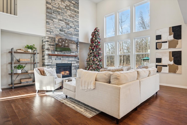 living room with a towering ceiling, a fireplace, and dark wood-type flooring