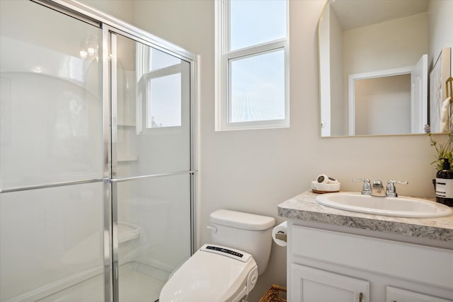 bathroom featuring vanity, toilet, and a shower with shower door