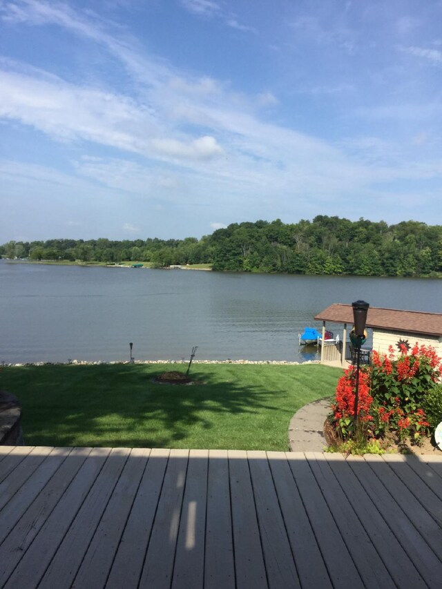 wooden terrace featuring a water view and a yard