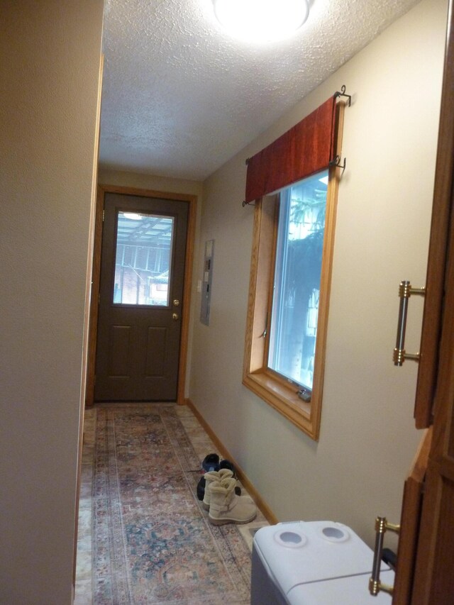 doorway to outside featuring a textured ceiling and electric panel