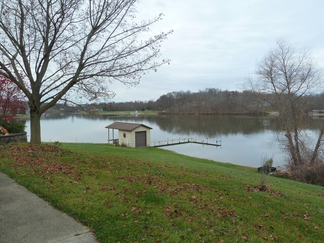 view of dock with a water view and a lawn