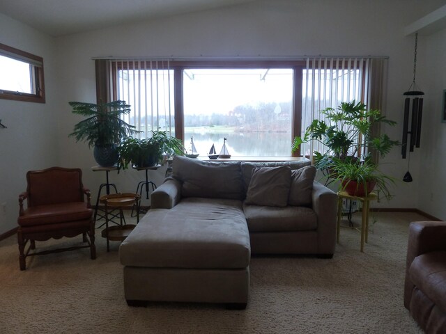 carpeted living room featuring a water view and lofted ceiling