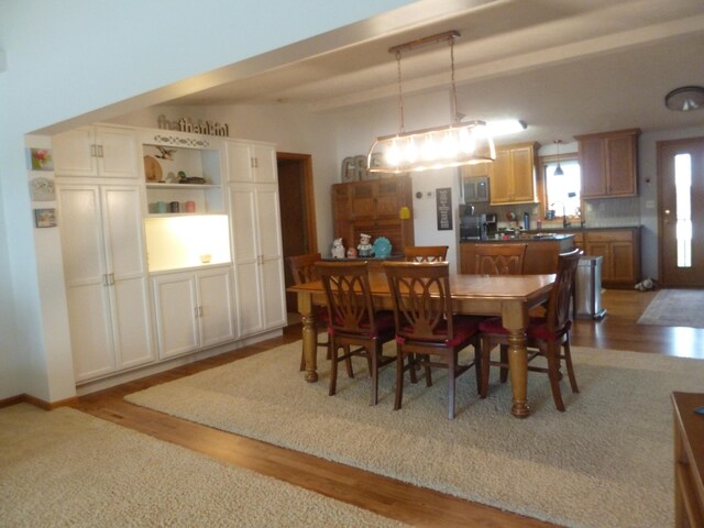 dining area featuring beamed ceiling and wood-type flooring