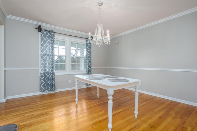 unfurnished dining area with light hardwood / wood-style floors, an inviting chandelier, and ornamental molding