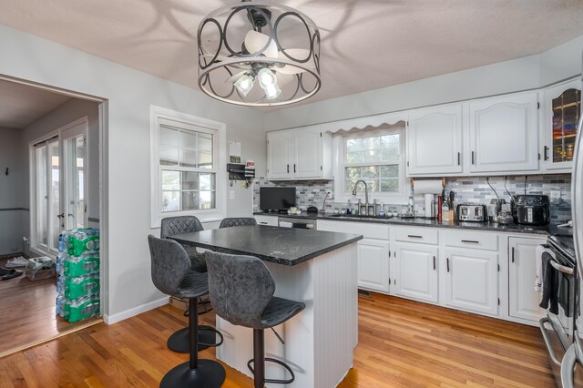 kitchen featuring white cabinets, a kitchen breakfast bar, a kitchen island, and sink