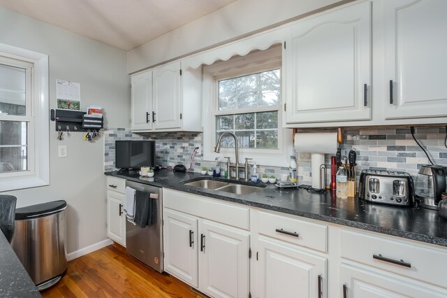 kitchen with sink, dark wood-type flooring, stainless steel dishwasher, decorative backsplash, and white cabinets