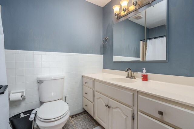 bathroom with vanity, toilet, and tile walls