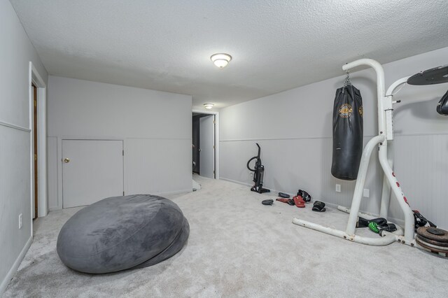 workout room with light colored carpet and a textured ceiling