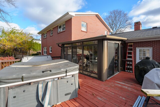 deck featuring a hot tub and a sunroom