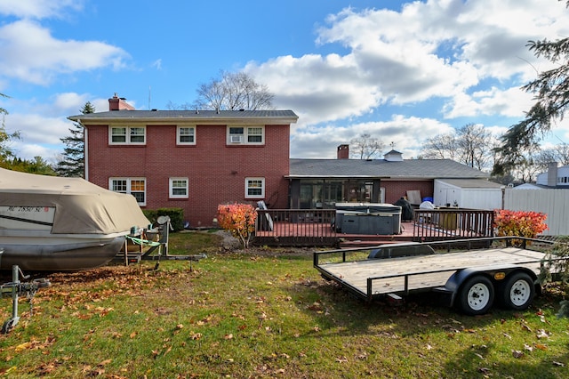 back of property featuring a sunroom, a yard, a hot tub, and a deck