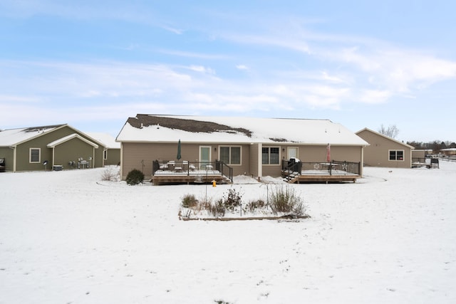 snow covered back of property featuring a deck