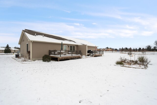 snow covered rear of property with a wooden deck