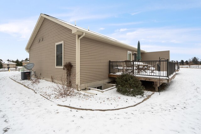 view of snowy exterior with central AC unit and a wooden deck