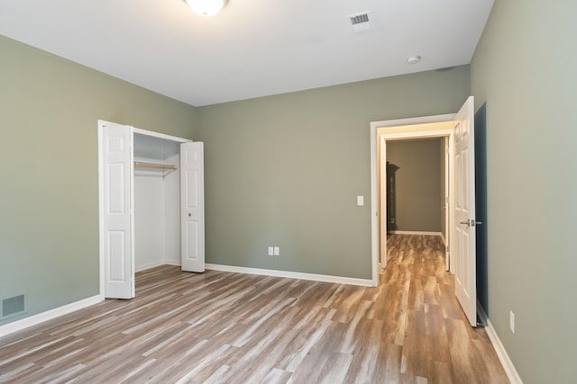 unfurnished bedroom with light wood-type flooring and a closet