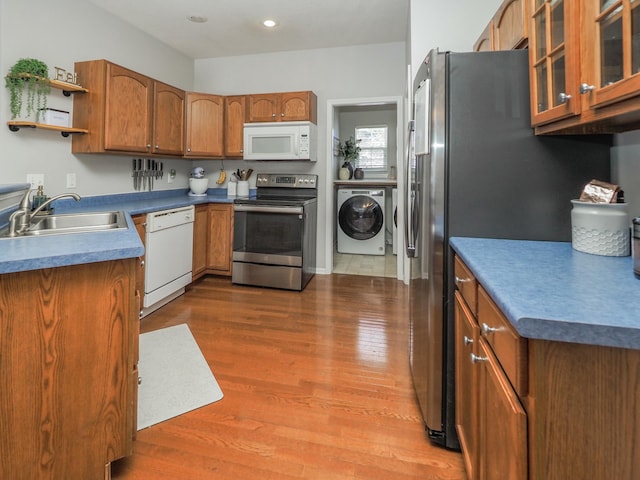 kitchen featuring hardwood / wood-style floors, washer / clothes dryer, sink, and appliances with stainless steel finishes