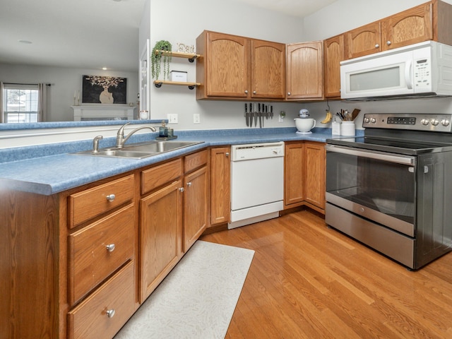 kitchen with kitchen peninsula, white appliances, light hardwood / wood-style floors, and sink