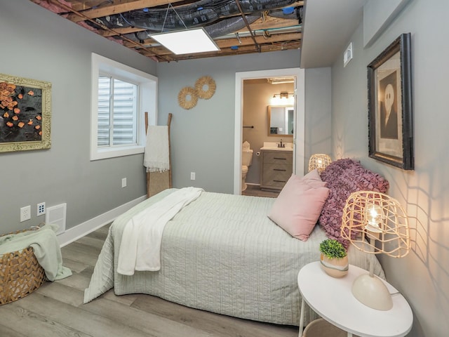 bedroom with connected bathroom, hardwood / wood-style flooring, and sink