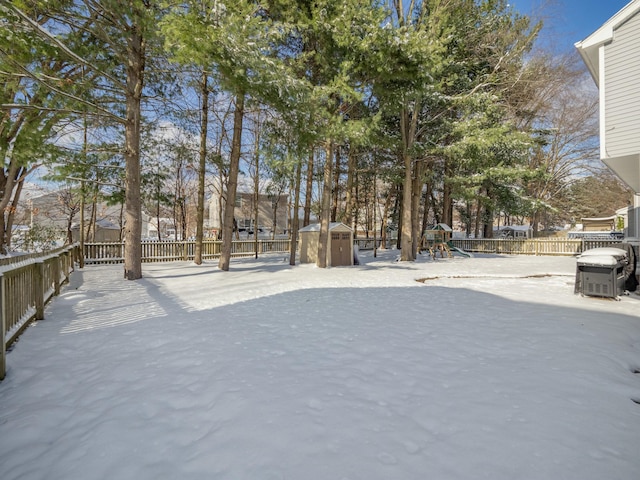 snowy yard with a playground and a storage unit