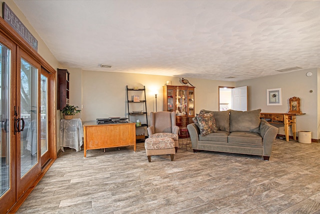 living room with french doors, wood-type flooring, and a textured ceiling