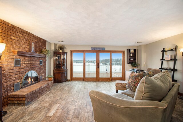 living room with hardwood / wood-style floors, a textured ceiling, and a brick fireplace