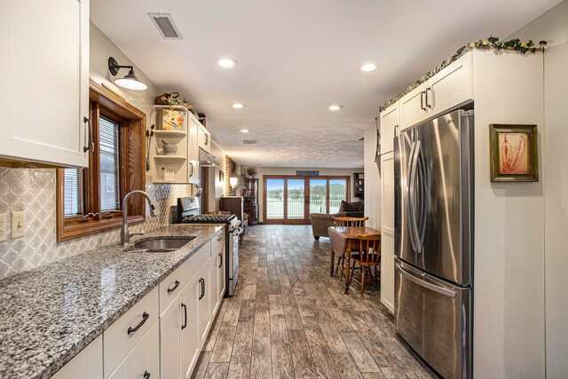 kitchen with white cabinets, dark hardwood / wood-style flooring, appliances with stainless steel finishes, and tasteful backsplash