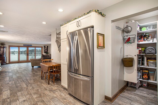 kitchen featuring wood-type flooring, white cabinetry, stainless steel refrigerator, and french doors