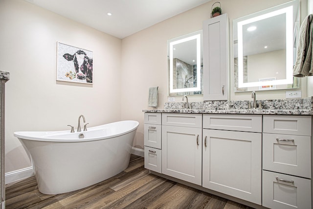 bathroom with a washtub, wood-type flooring, and vanity