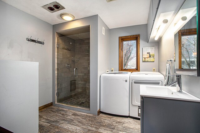 bathroom featuring washer and dryer, hardwood / wood-style flooring, an enclosed shower, and a healthy amount of sunlight