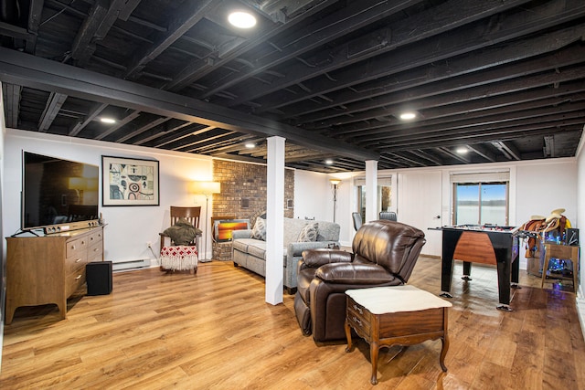 living room with light hardwood / wood-style floors, baseboard heating, and brick wall