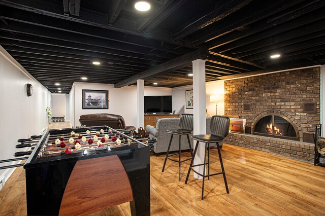 rec room with a fireplace, beam ceiling, and light hardwood / wood-style floors