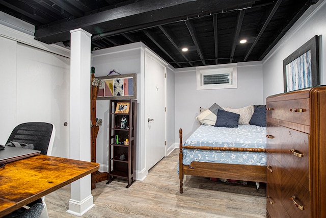 bedroom featuring beamed ceiling, light wood-type flooring, and a closet