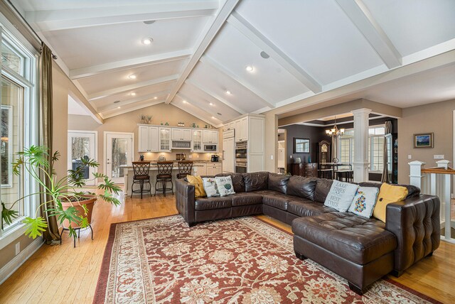 living room featuring vaulted ceiling with beams, light hardwood / wood-style floors, and a notable chandelier