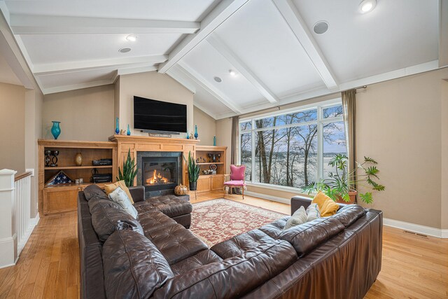 living room with vaulted ceiling with beams and light wood-type flooring