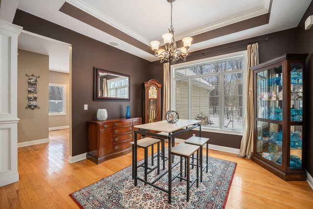 dining room featuring a tray ceiling, ornamental molding, a notable chandelier, and light wood-type flooring