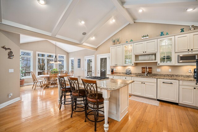 kitchen featuring a kitchen bar, pendant lighting, white cabinetry, light hardwood / wood-style floors, and a kitchen island