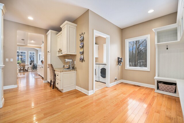 laundry room with washing machine and dryer, cabinets, and light wood-type flooring