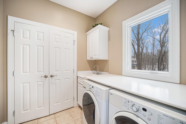 laundry area featuring cabinets, light tile patterned floors, sink, and washing machine and clothes dryer