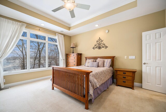 carpeted bedroom with a raised ceiling, ceiling fan, and ornamental molding