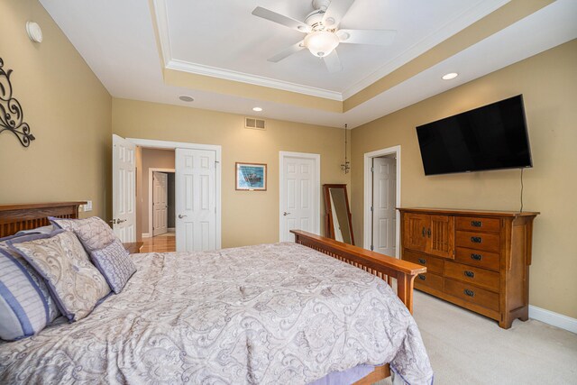 carpeted bedroom with a raised ceiling, ceiling fan, and ornamental molding