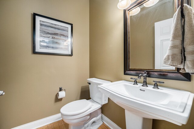 bathroom with hardwood / wood-style floors, toilet, and sink