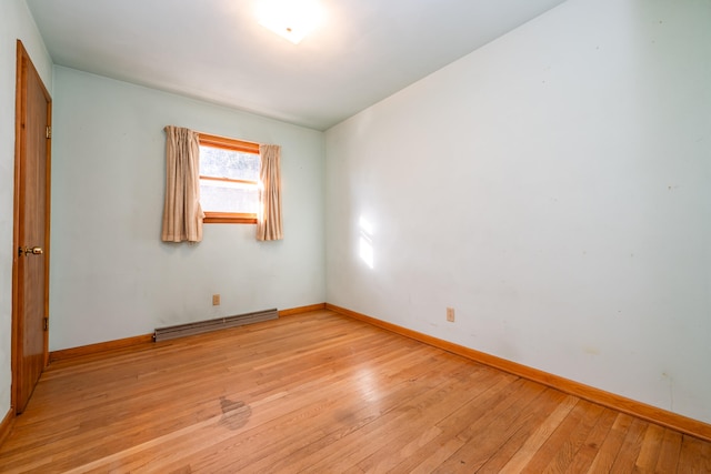 empty room with light hardwood / wood-style flooring and a baseboard heating unit