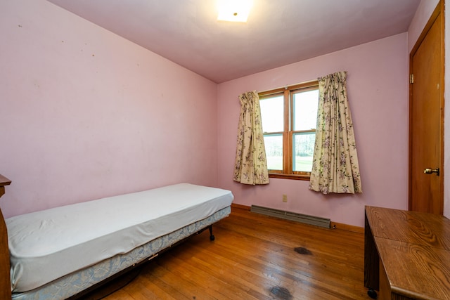 bedroom with hardwood / wood-style floors and baseboard heating