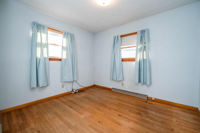 unfurnished room featuring a baseboard heating unit and light wood-type flooring