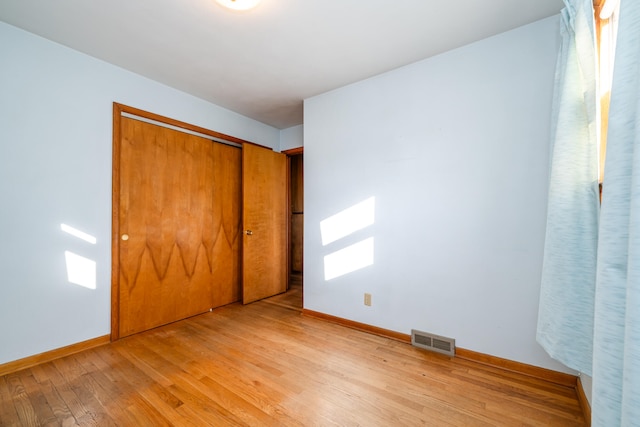 unfurnished bedroom with light wood-type flooring and a closet