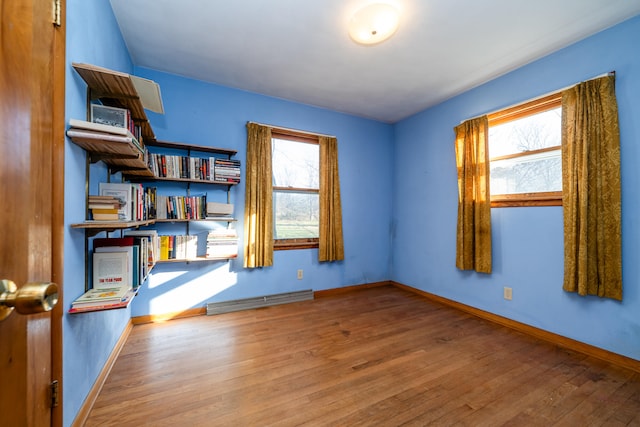 unfurnished room featuring hardwood / wood-style floors, plenty of natural light, and a baseboard radiator