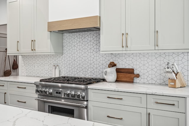 kitchen featuring decorative backsplash, light stone counters, custom range hood, high end stove, and white cabinetry