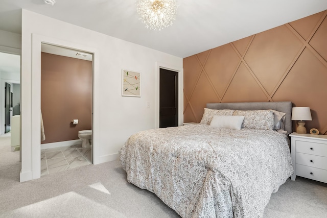 bedroom with light colored carpet, ensuite bath, and a notable chandelier